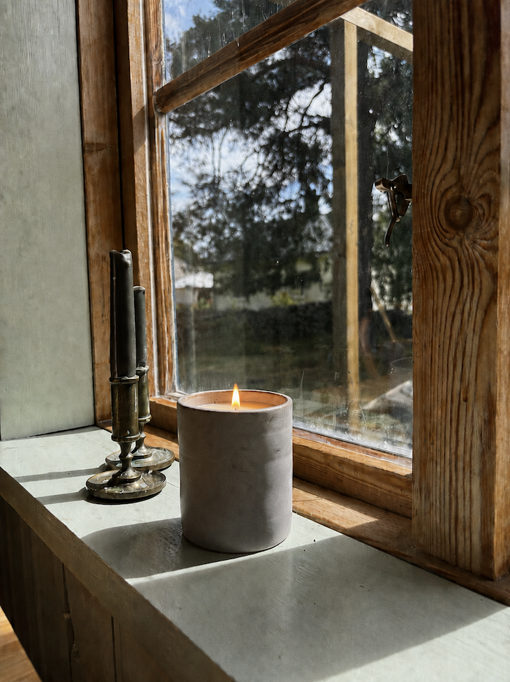 Cozy cottage nook in summer lighting with lit candle.