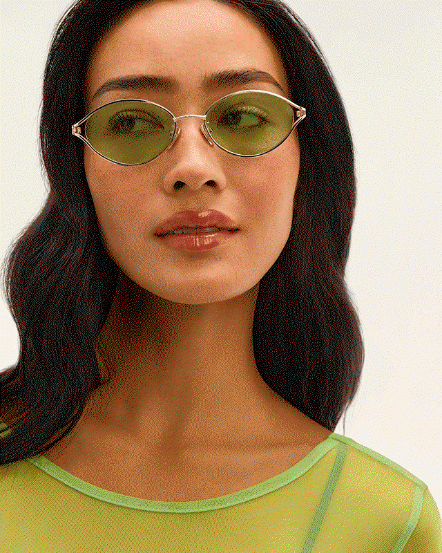 GIF of woman wearing green tinted round sunglasses and man dressed in green wearing the same green-tinted round sunglasses.