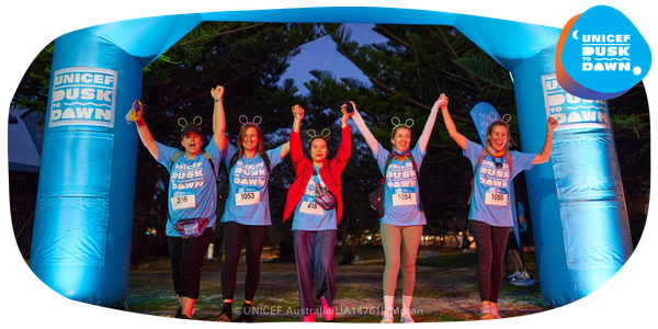 A smiling group of women crossing a start line.