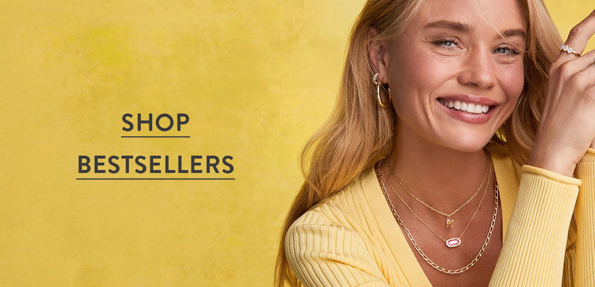 Shop bestsellers. Smiling woman wearing layered gold necklaces against a yellow background.