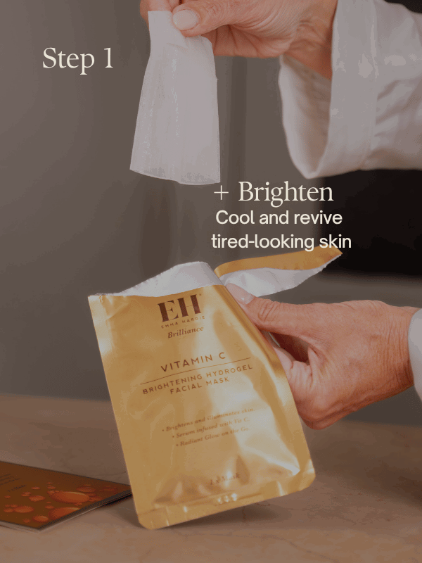 Hands removing an Emma Hardie Vitamin C Brightening Hydrogel Facial Mask from its gold sachet.