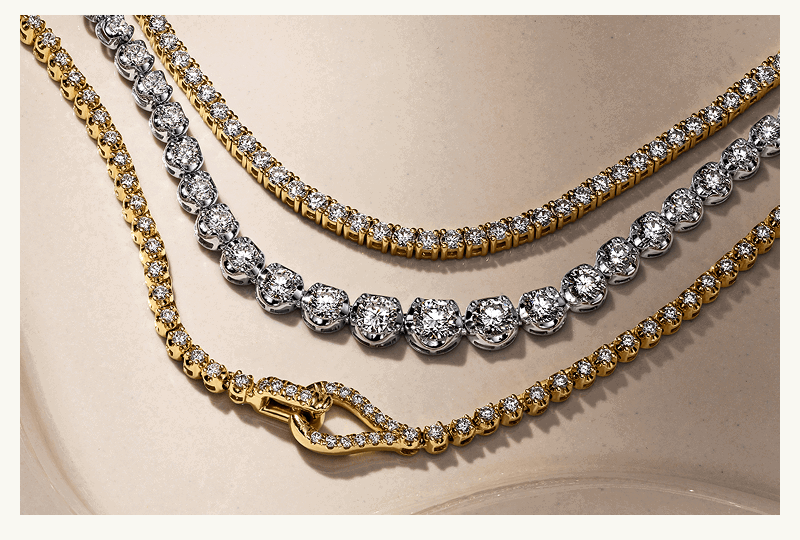 Three layered tennis necklaces made of round-cut diamonds, set in different metals.