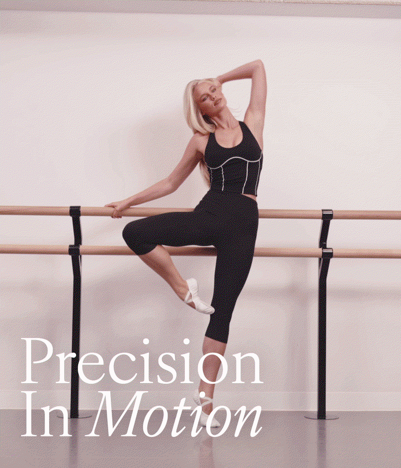 Precision In Motion. Woman in a black crop and cropped leggings at a ballet barre.