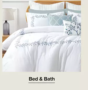 A bed with white and blue bedding. Shop bed and bath.