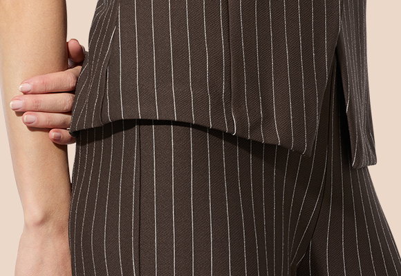 Frauenmodel trägt braunen Hosenanzug mit weißen Streifen, Vorderansicht
