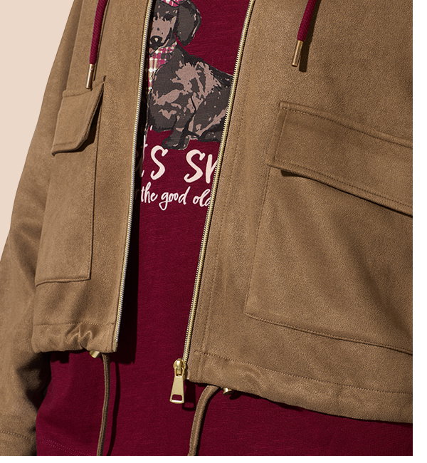 Frauenmodel trägt braune Jacke mit aufgesetzten Taschen, goldener Reißverschluss, bordeauxrotes Oberteil mit Hundemotiv, Vorderansicht