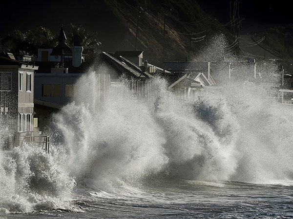Huge waves crash against beachfront homes.