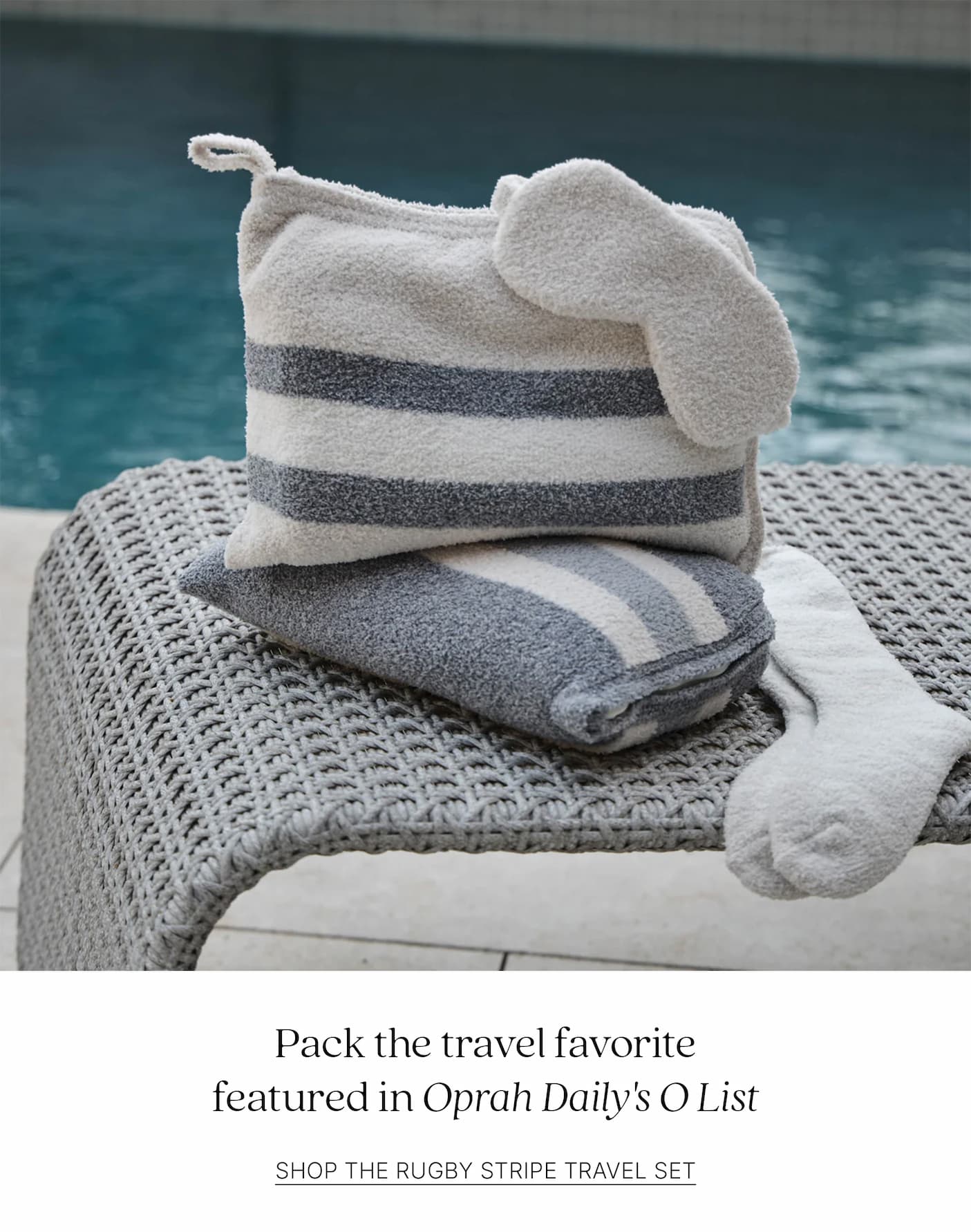 Kashwére Rugby Stripe Travel Set with matching pouch, half blanket, ribbed socks, and eye mask displayed poolside. Featured in Oprah Daily's O List.
