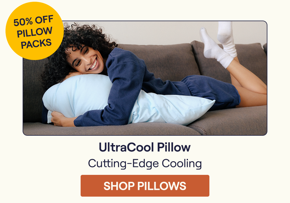 Woman laying on a bed hugging the UltraCool Pillow