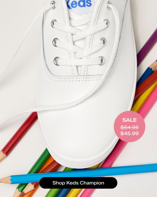 A close-up overhead view of the Original Keds Champion Leather Lace-Up in white with an array of colored pencils. A pink circle shows the style was $64.94 and is on sale for $45.99. Shop Keds Champion
