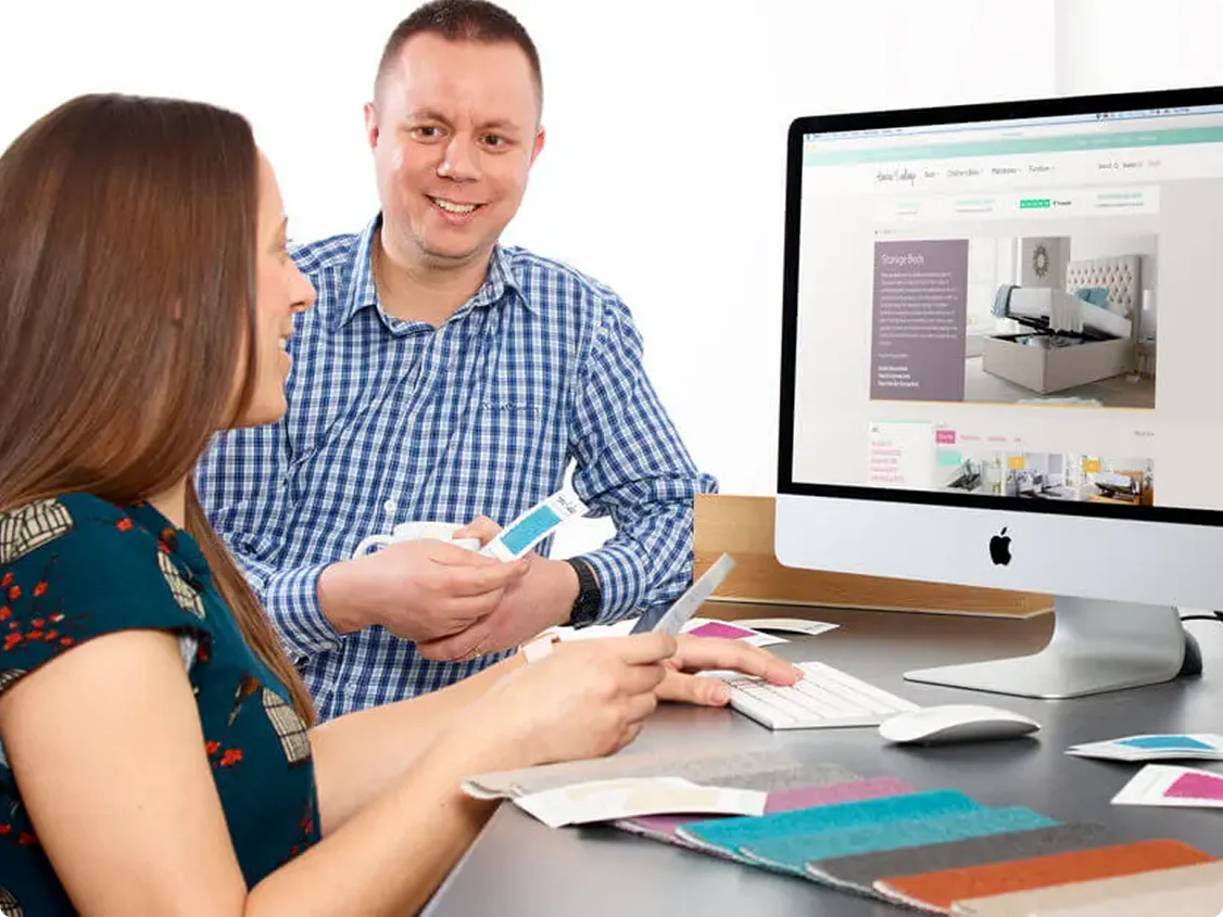 A woman and man, discussing which bed to buy at the computer.