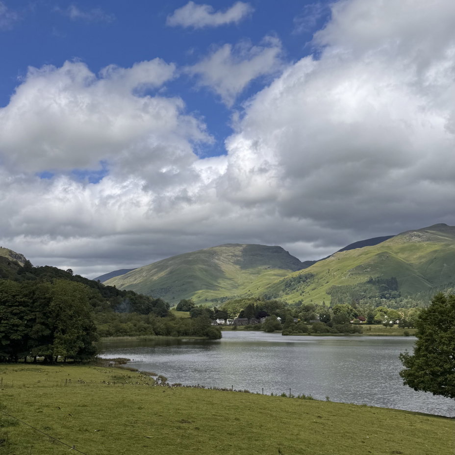 A lake with green hills and the sky in the background.