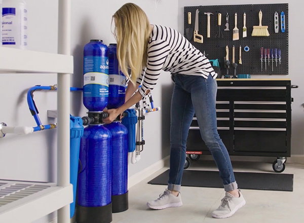 Woman installing whole house filter system in a garage