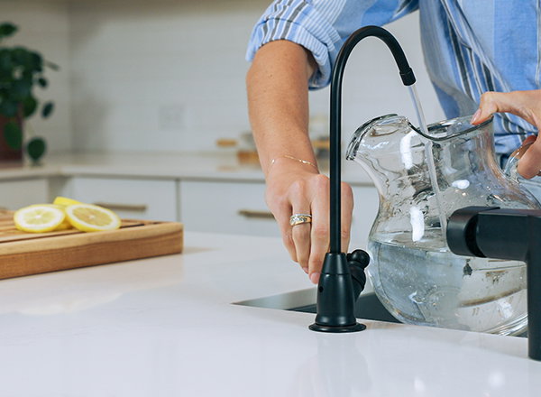Woman filling pitcher with filtered water