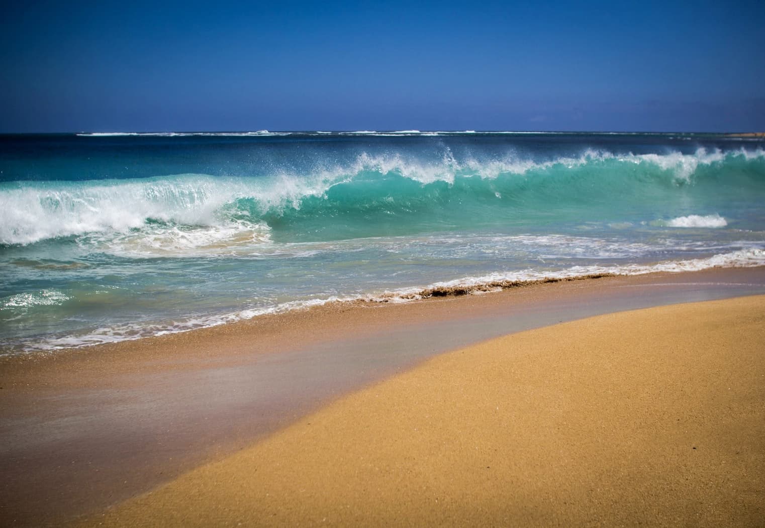 An idyllic beach with crashing waves and blue sky