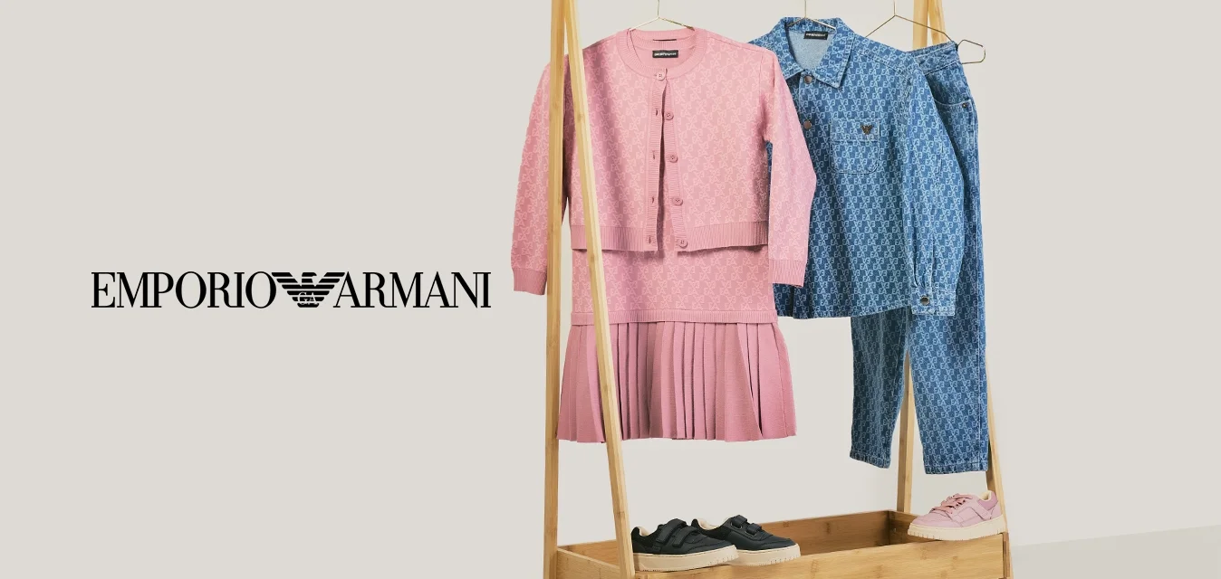 Houten kledingrek met een roze gebreide jurk en cardigan, een blauw gemusterd shirt en jeans, zwarte en roze sneakers op en onder het rek.