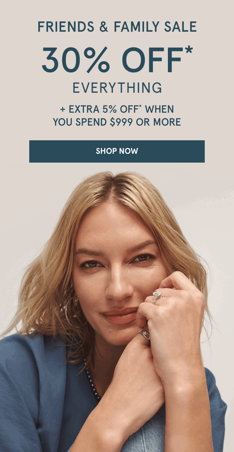 Woman wearing hoops, ring and a diamond engagement ring resting her hands near face. Friends and family sale. Click shop now.