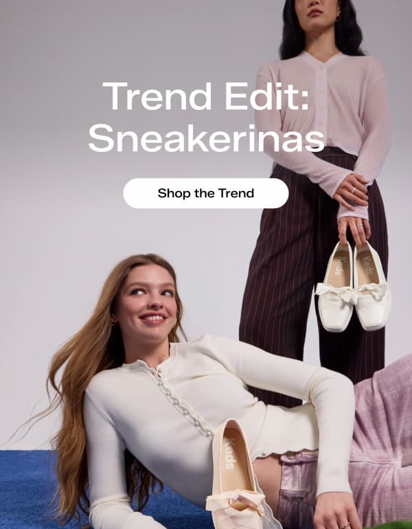 Two women in stylish outfits paired with the Square Toe Ballet flats. One woman is standing in the background, she is wearing a light pink cardigan sweater, brown pin-striped trousers and the Square Toe Ballet Pearlized Leather flats in white. The woman in the foreground is lounging on a blue carpet, she is wearing a cream-colored button-up sweater, pink jeans, and the Square Toe Ballet Leather flats in blush. Text overlaid on the image says Trend Edit: Sneakerinas. Shop the Trend. 