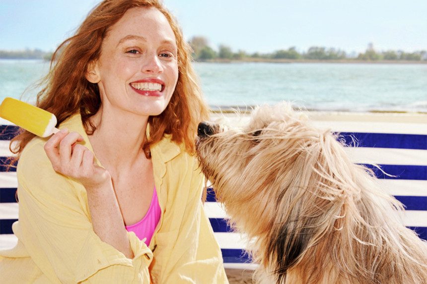 Frau mit Hund am Strand.