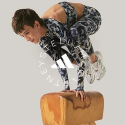 Persona con ropa deportiva equilibrándose sobre las manos encima de un potro de gimnasia contra un fondo liso.