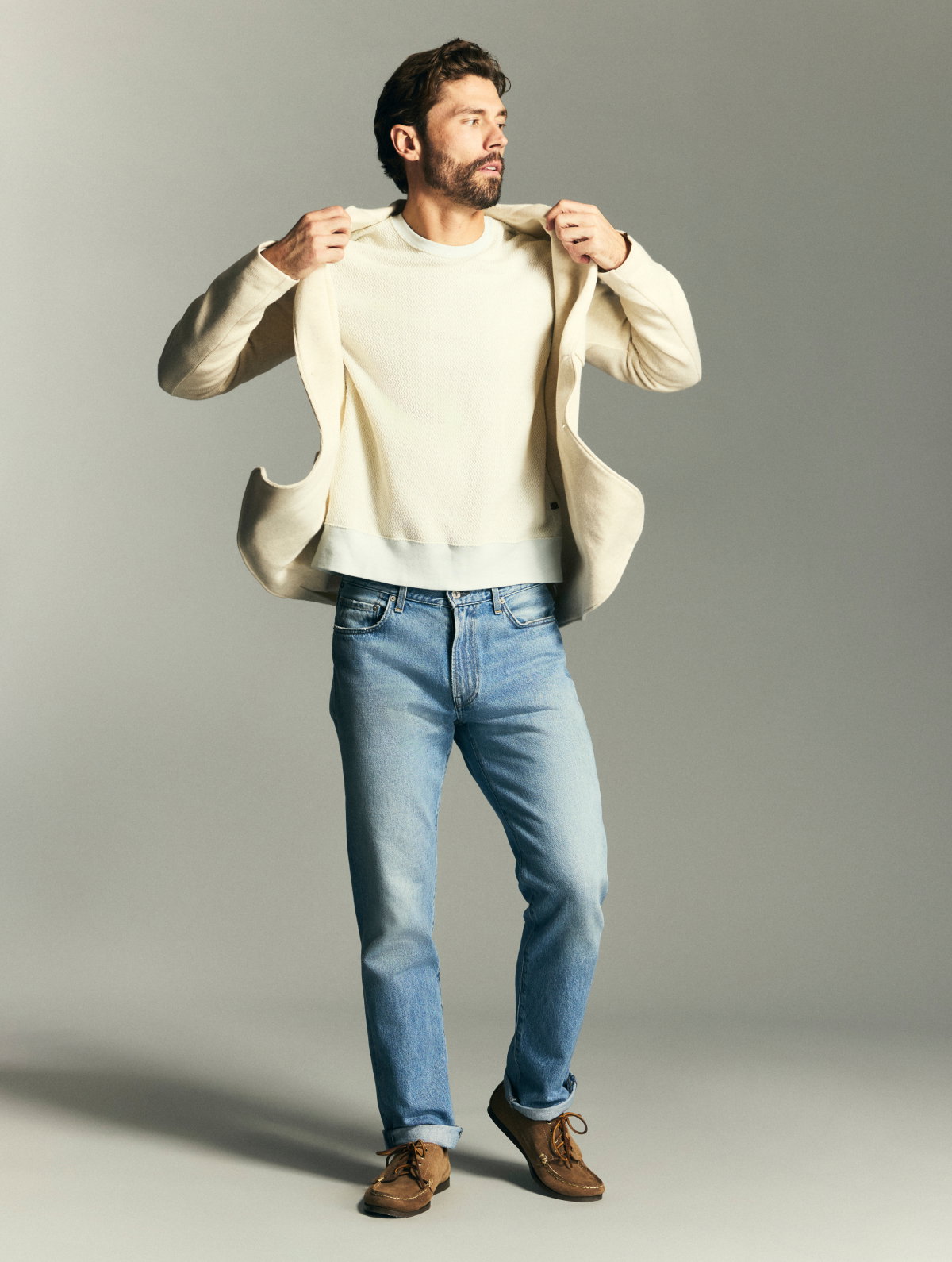 Model pulls a knit sport coat over a cream sweater.