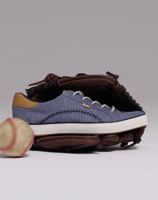 A short video of a baseball rolling toward the Center III Pennant Chambray Lace-Up sneaker in blue which is sitting in a brown leather baseball glove.