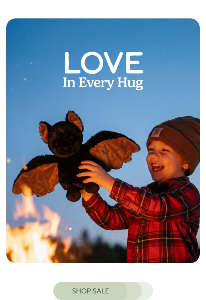 A little kid playing with Bat Warmies in front of a campfire. Shop Sale.