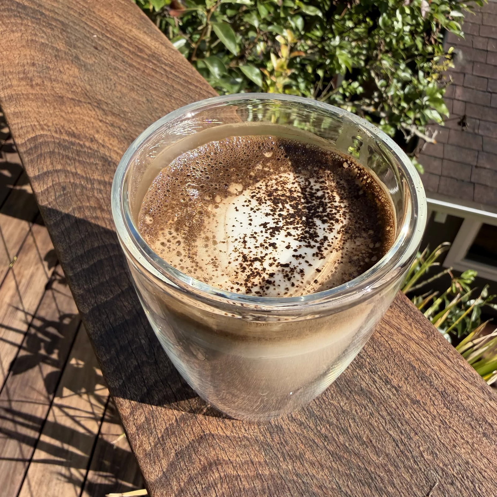 Delicious hojicha latte on a sun-lit balcony railing