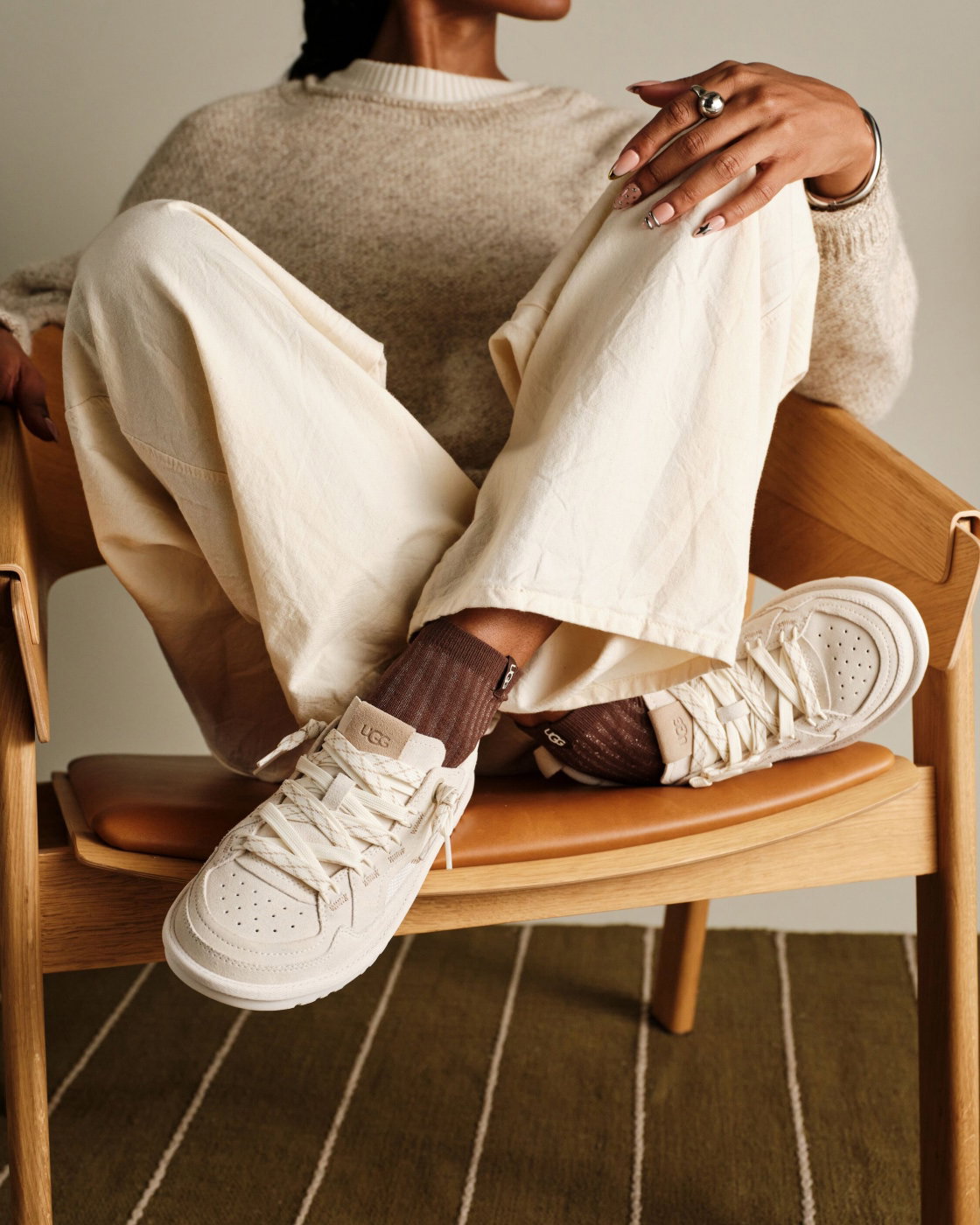 A person sat with their legs up on a chair, wearing the Minimel trainer.