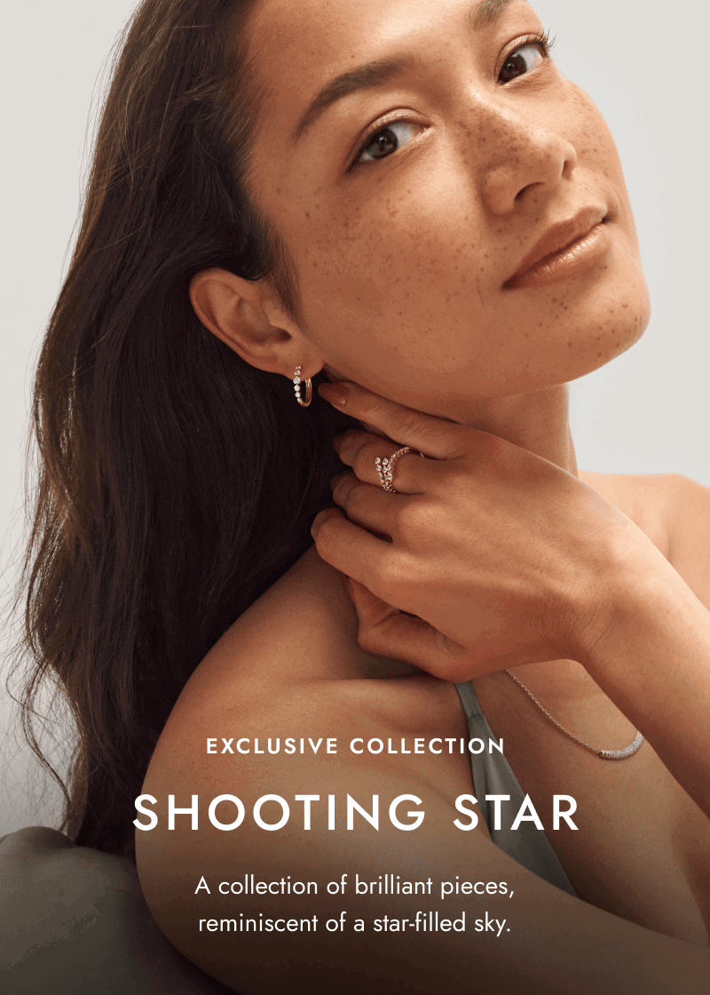 Woman wearing yellow gold diamond hoops, necklace and ring. Shooting star. Brilliant pieces reminiscent of a star-filled sky.
