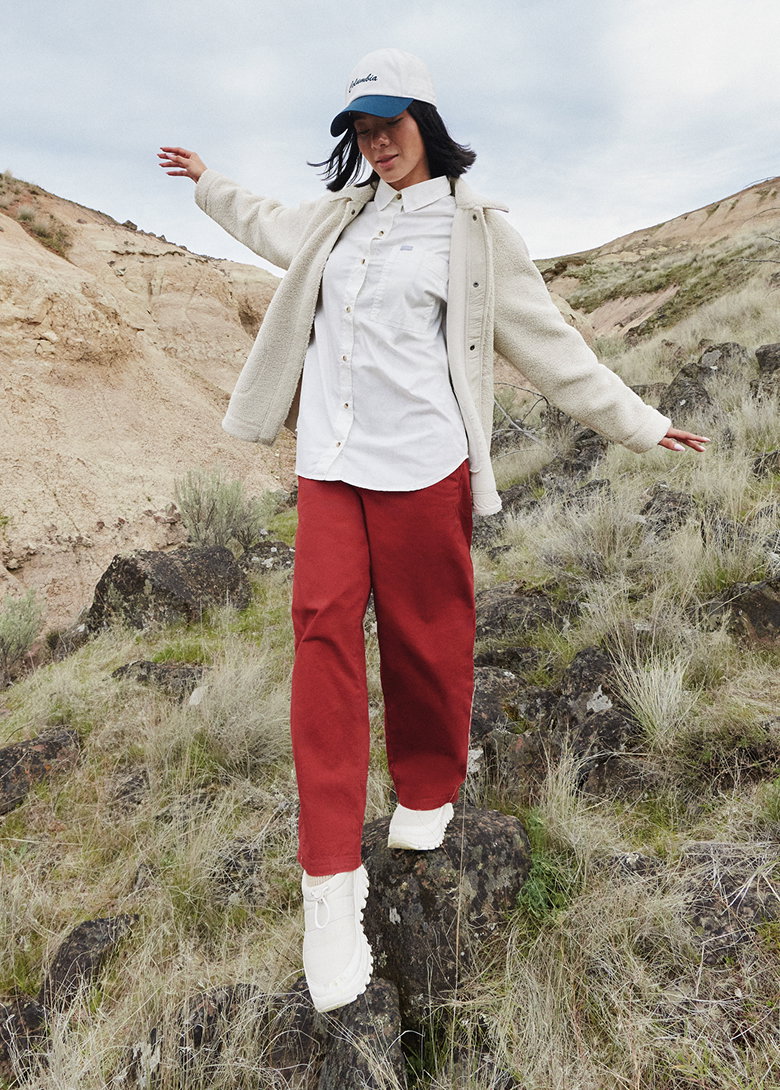 A woman in fall layers on a grassy hill.