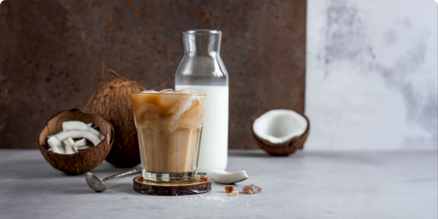 Glass of iced coconut latte served with fresh coconut pieces and coconut milk