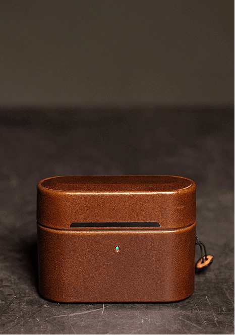 Front view of a brown leather AirPods case with a status light cutout and a leather pull tab.