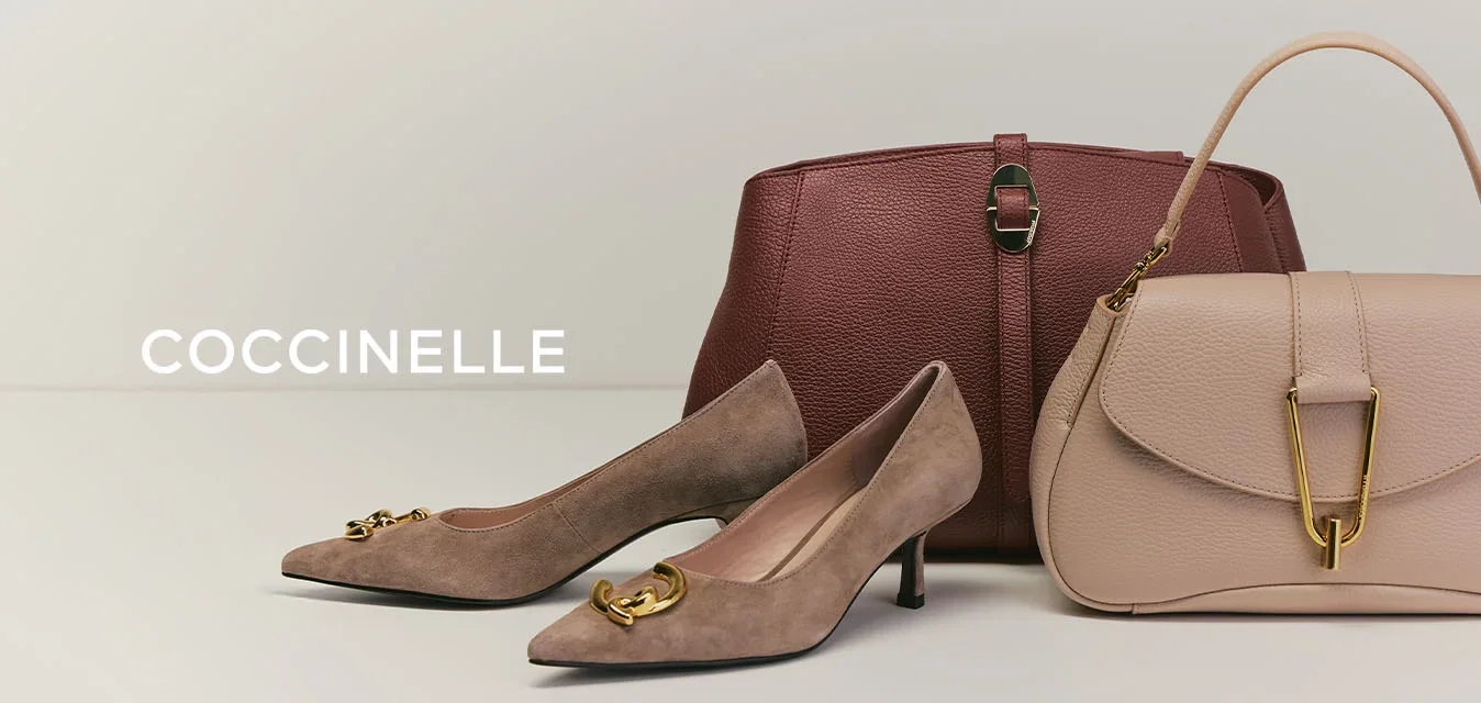 Paar bruine suède lage hak schoenen met gouden gesp, bruine lederen handtas met sluiting en beige handtas met gouden gesp op witte ondergrond.