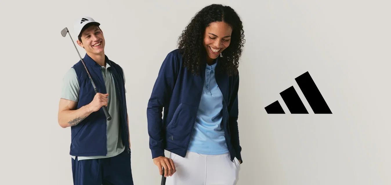 Twee golfers die glimlachen en met clubs poseren, gekleed in marineblauwe en lichtblauwe sportkleding, tegen een effen lichte achtergrond.