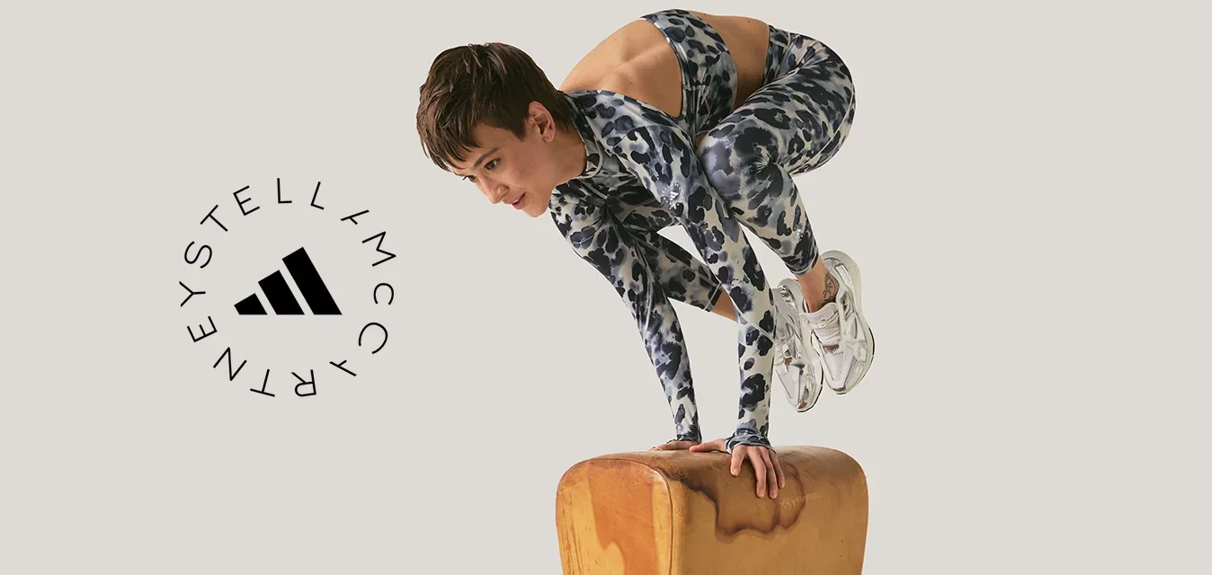 Persoon in sportkleding balanceert op handen op een turnpaard tegen een effen achtergrond.