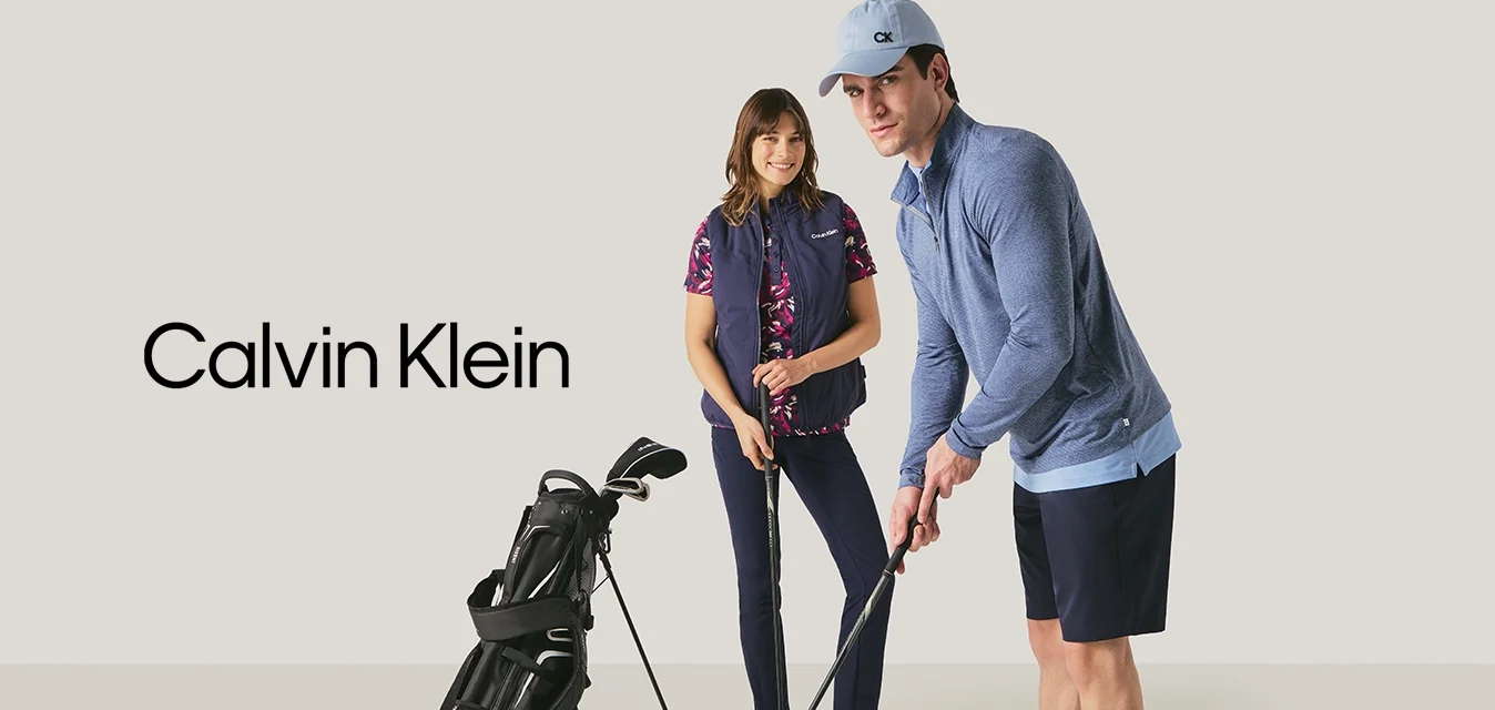 Man en vrouw bereiden zich voor om binnen golf te spelen met golfclubs en een golftas tegen een neutrale achtergrond.