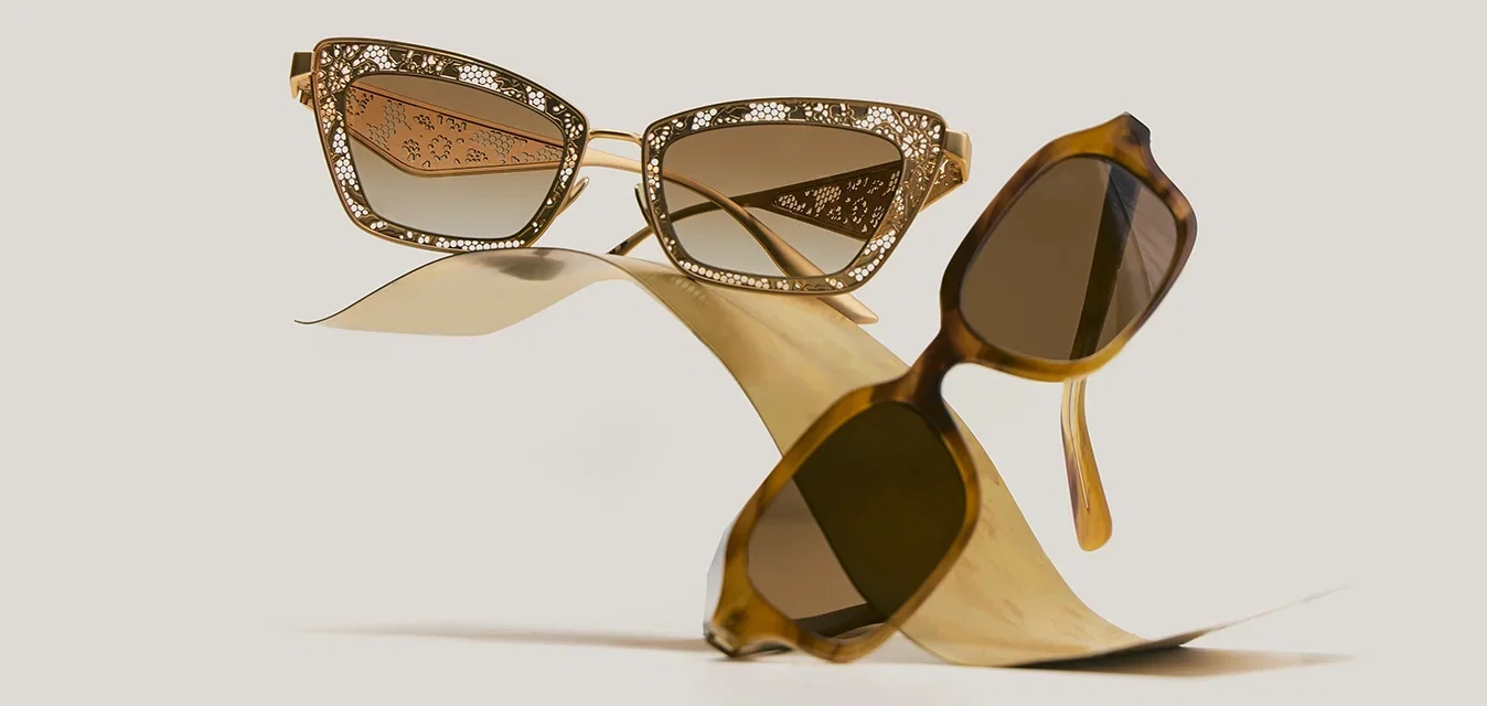 Due paia di occhiali da sole con lenti sfumate marroni, uno con una montatura cat-eye con motivo floreale e l'altro con una montatura classica tartarugata.