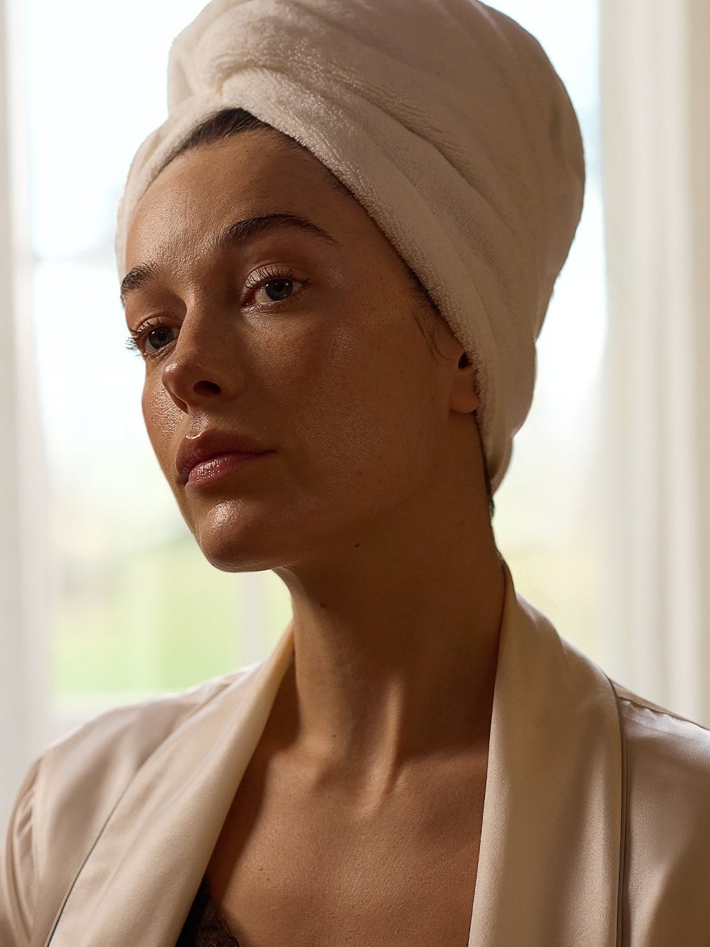 Women looking into mirror with hair in a towel turbin. 