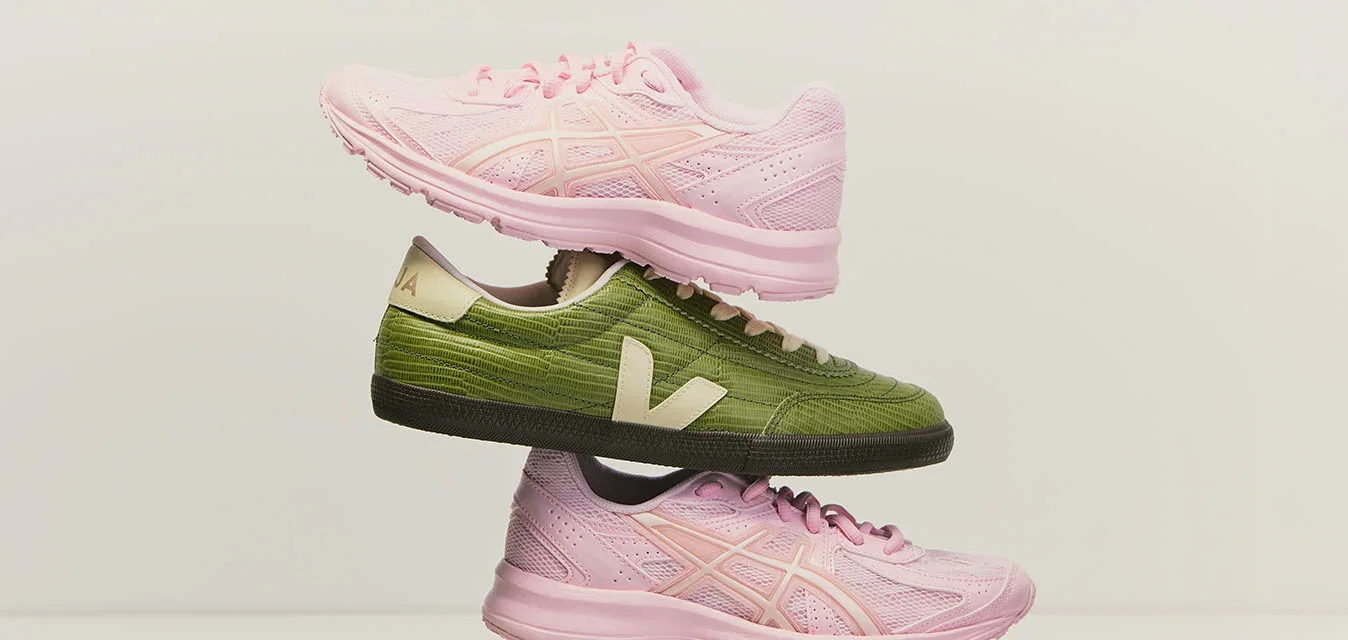 Dos zapatillas rosas y dos zapatillas verdes con logotipos blancos están apiladas alternativamente en una disposición vertical equilibrada sobre un fondo liso.