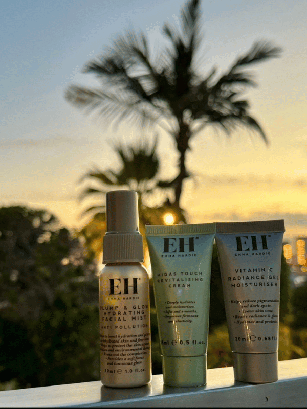 Emma Hardie travel-size skincare products beside a pool at sunset.