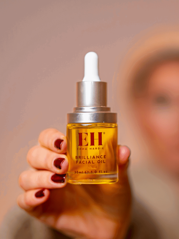 Hand holding a full-size Emma Hardie Brilliance Facial Oil bottle.
