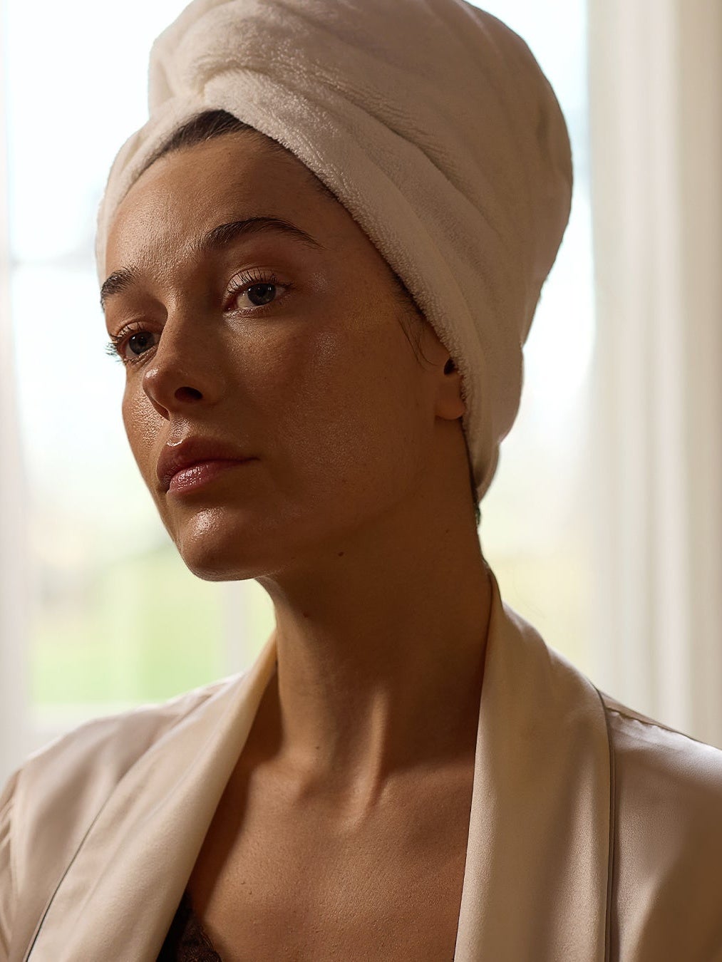 Women looking into mirror with hair in a towel turbin. 