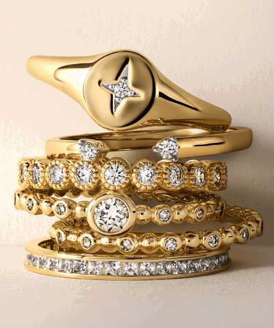 Yellow gold diamond rings including a compass-style signet ring, solitaire and pavé stackable bands.