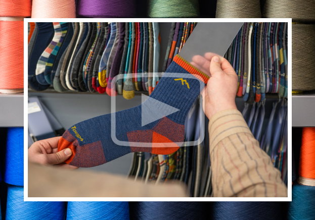 Watch the Video - a worker inspects a 1466 sock, hanging on a rack of samples