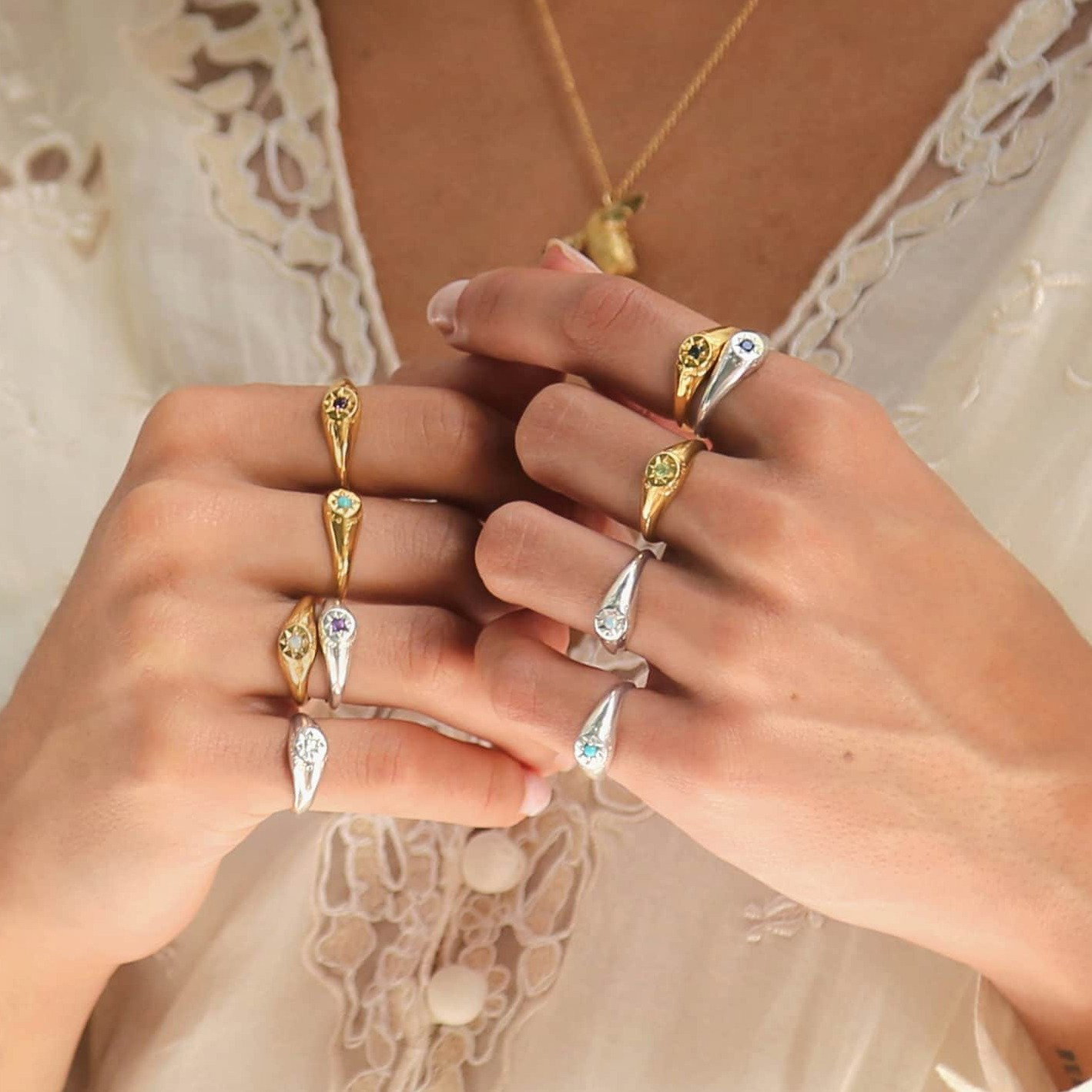 Hand wearing a selection of gold Birthstone Signet Rings featuring colourful gemstones.