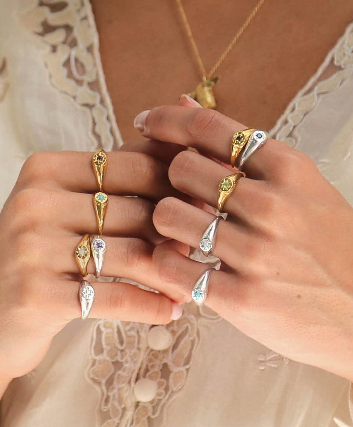 Hand wearing a selection of gold Birthstone Signet Rings featuring colourful gemstones.