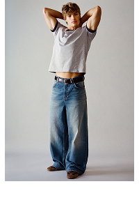 Model wearing white tank top and blue jeans, hands behind head