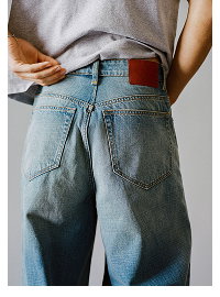Person wearing light wash jeans with brown leather belt