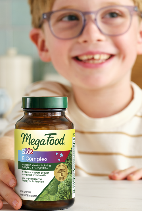 Boy with glasses holding MegaFood Kids B Complex Minis